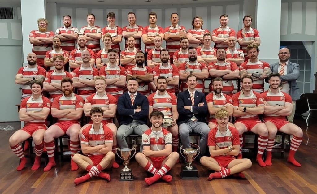 VRC Rugby men's senior squad formal team photo in the Vancouver Rowing Club clubhouse with BC Rugby trophies